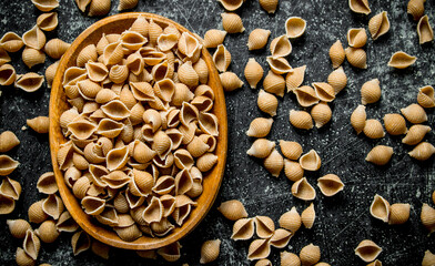 Pasta background. Dry pasta conchille in bowl.