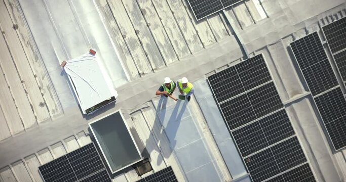Solar energy, drone and construction workers on rooftop for engineering, architecture or grid. Aerial view, solar panels and industrial team working on project management, city logistics and building