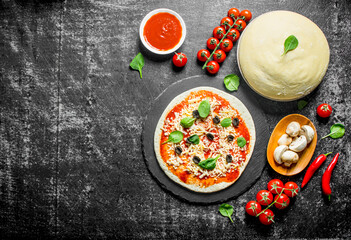 Raw pizza. Dough with tomato paste, mushrooms, olives and chili pepper.