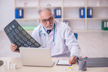 Old male doctor radiologist working in the clinic