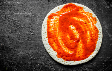 Raw pizza. Rolled out dough with tomato paste.