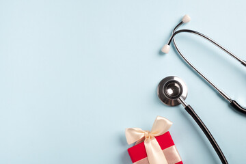 Doctors day and World health day. Medical stethoscope with gift box on pastel blue background....