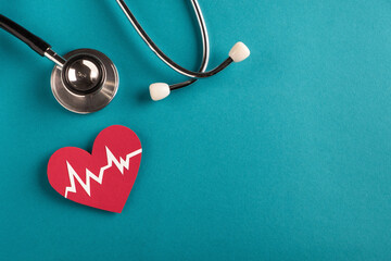 Heart health and medical concept. Medical stethoscope and cardiogram on red heart on bright blue...