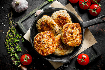 Cutlets in pan with thyme,garlic and tomatoes.
