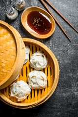 Fragrant manta dumplings in a bamboo steamer with soy sauce.