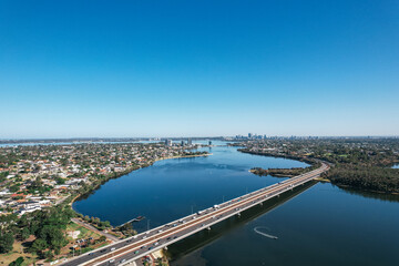 Aerial view of the Canning River and Mount Henry freeway bridge with the Perth city skyline in the distance.