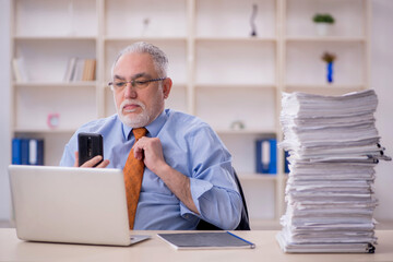 Fototapeta premium Old male employee unhappy with excessive work in the office