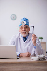 Old male docror otolaryngologist working in the clinic
