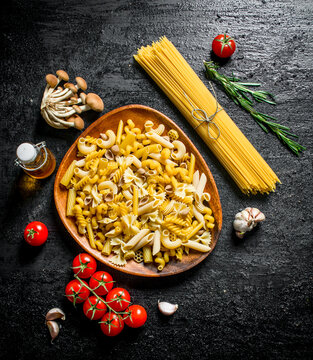 Raw pasta assortment with rosemary,tomatoes and mushrooms.