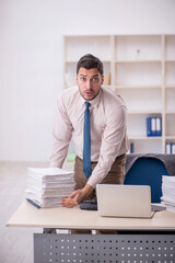 Naklejka premium Young male employee unhappy with excessive work in the office