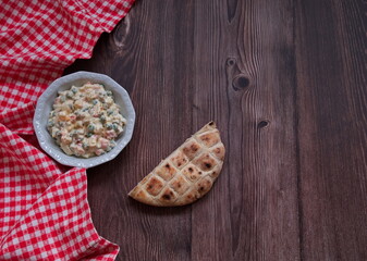 Top view of French salad on wooden background with piece of bread