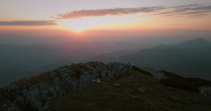 Drone shot of distancing it from the top of mountain Peca in the early morning with a orange sunrise.