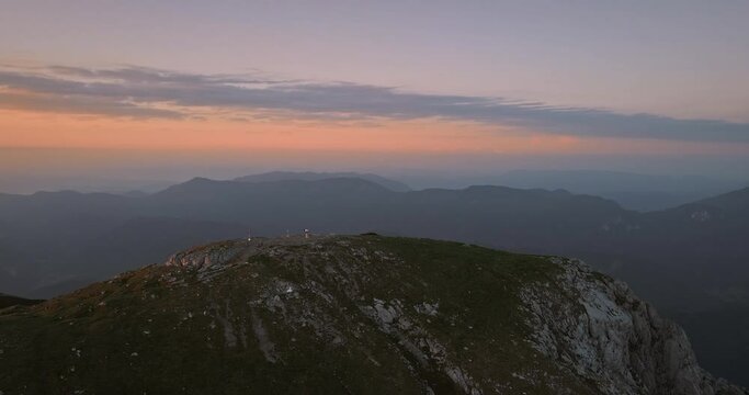 Drone shot of the mountain Peca in the eary morning. Ligt orange colors on the sky in company with blue clouds.