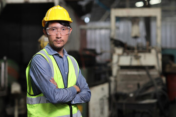 Confident asian technician engineer and worker in protective uniform standing and looking away while controlling operation checking industry machine process at industry manufacturing