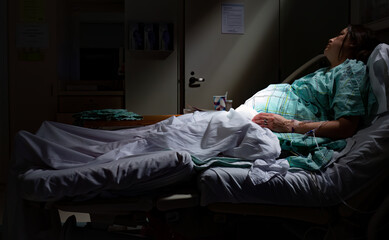 Pregnant woman in labor laying in hospital bed. Light rays belly stomach maternity ward