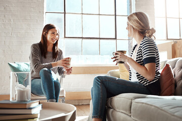 Woman, friends and smile for coffee, conversation or social catch up relaxing together on living room sofa at home. Happy women enjoying tea time, chatting or gossip with drink in apartment on couch