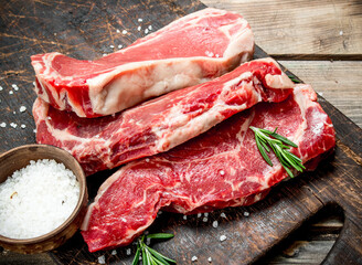 Raw marbled beef steaks with salt and aromatic spices.