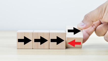 Hand flip over wooden cube block with red arrow facing the opposite direction black arrows, Unique,...