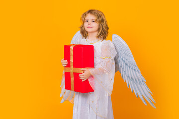 Angel kid with gift box present. Kid wearing angel costume white dress and feather wings. Innocent...
