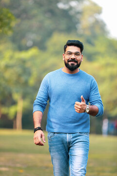Young indian man showing thumps up at park.