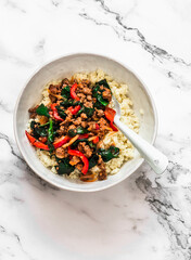 Couscous with lamb minced meat, red sweet pepper, spinach tomato sauce on a light background, top view
