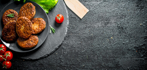Cutlets on a plate with salad leaves and tomatoes.