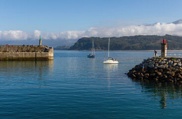 Fototapeta na wymiar Actividad con gente y barcos en la entrada al puerto de Lastres en Asturias, Españ