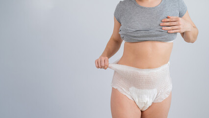 Woman in adult diapers on a white background. Incontinence problem. - obrazy, fototapety, plakaty