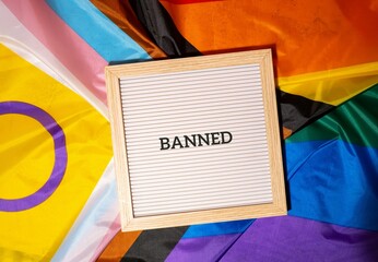BANNED text frame on Rainbow LGBTQIA flag made from silk material. Symbol of LGBTQ pride month....