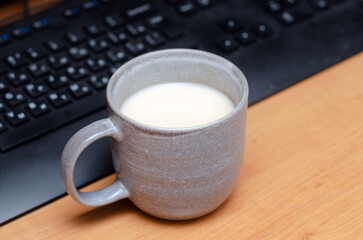 a large mug of milk on a computer desk