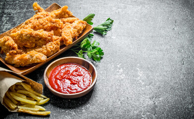 Chicken strips with parsley, French fries and tomato sauce in bowl.
