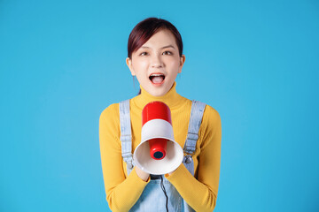 Young Asian girl using megaphone on blue background