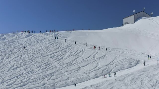 People tourists riding skiing snowboarding on snow slope turn track ski resort outdoor extreme sport activity top shot aerial view. Drone adrenaline alpine speed racing downhill frozen route winter 4k