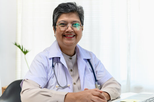 Portrait photo of senior beautiful Asian doctor video remote conference call online with patient for social distancing due to covid-19 pandemic. Technology, health care new normal online telehealth.