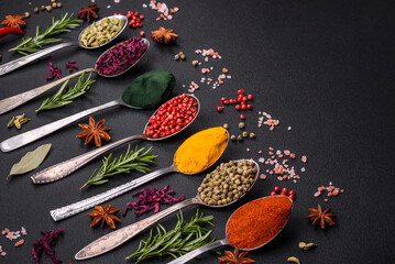 Variation of spices in metal spoons paprika, turmeric, cardamom, a mixture of allspice, thyme and rosemary