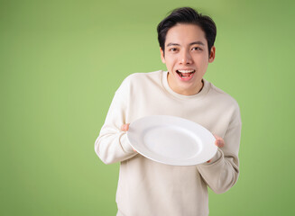 Image of young Asian man holding plate on background