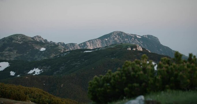 A shot of mountain Peca, thin clouds above, early morning light, patches of snow on the mountains.