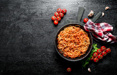 Spaghetti with Bolognese sauce in pan with napkin, tomatoes and garlic.