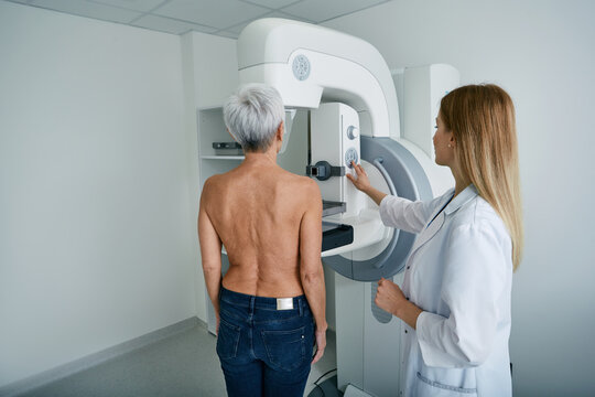 Mammography test. X-ray breast examination of mature female patient with radiology technician in mammography radiology room at medical clinic