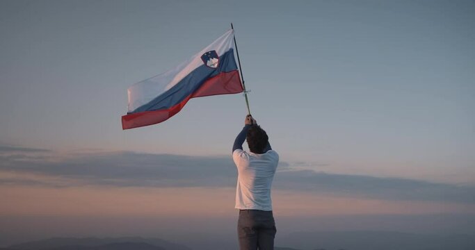 Hiker holding a pole in the air with a hiking pole to let it flutter in the wind. Blue red sky in the morning with some clouds.