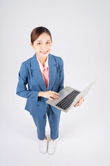 Full length photo of young Asian businesswoman using laptop