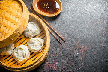 Hot aromatic manta dumplings in bamboo steamer with soy sauce.
