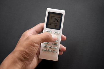 Hand pressing air conditioner remote control isolated on black background