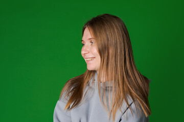 Dreamy woman in gray cozy sweatshirt. Front view interested girl isolated on green background. Happy caucasian woman
