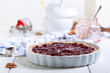Preparing a shortcrust pastry pie with berry jam for baking.