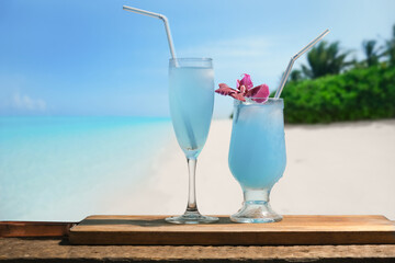 Blue lagoon cocktails, tropical beach on background. Summer resort concept.