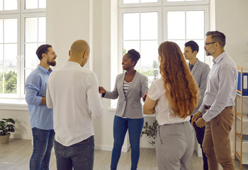 Friendly conversation of colleagues at work in office. Positive diverse work team in office having fun chatting, discussing work and sharing ideas. Multiracial men and women standing in circle.