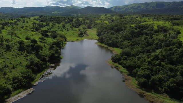 Nubes reflejadas en agua de lago rodeado de arboles verdes