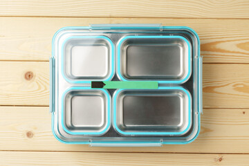 Metal lunch box with compartments on wooden background