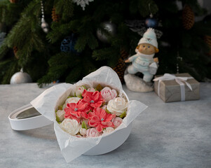 Marshmallow bouquet of flowers in a gift box on the background of a Christmas tree, the concept of a festive mood